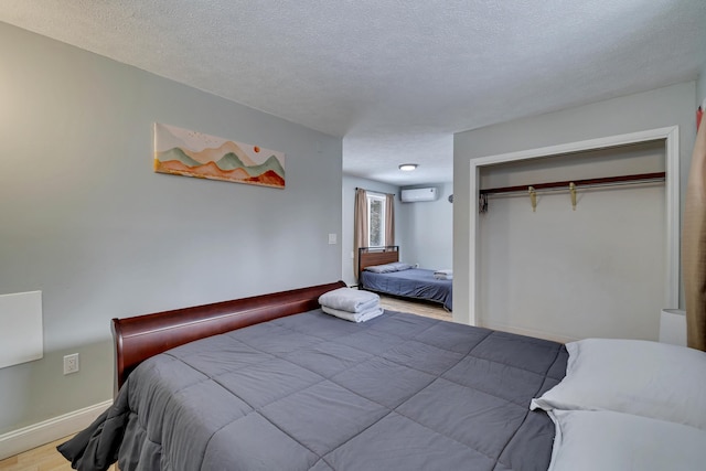 982 Long Ridge Rd, Hawley, PA 18428 - bedroom featuring a wall mounted air conditioner, baseboards, a textured ceiling, and wood finished floors
