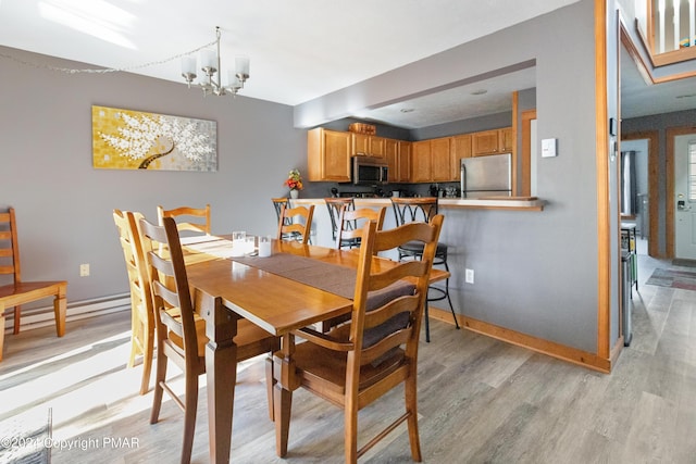 dining room featuring a notable chandelier, light wood-style flooring, and baseboards