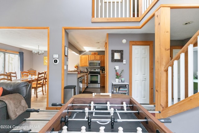 rec room featuring light wood-style floors and an inviting chandelier