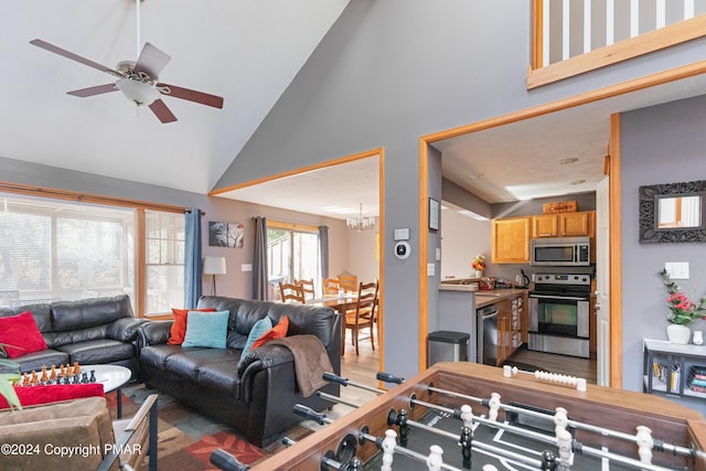 living area featuring high vaulted ceiling, wood finished floors, and ceiling fan with notable chandelier