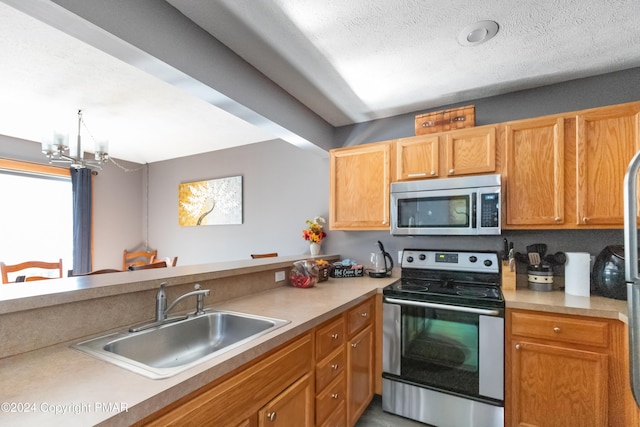 kitchen with a sink, stainless steel appliances, a textured ceiling, light countertops, and a notable chandelier