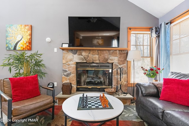 living room featuring vaulted ceiling and a stone fireplace