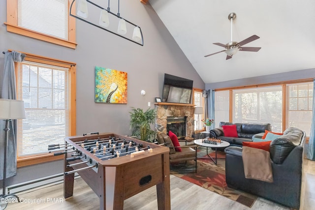 recreation room featuring high vaulted ceiling, a fireplace, wood finished floors, and a ceiling fan