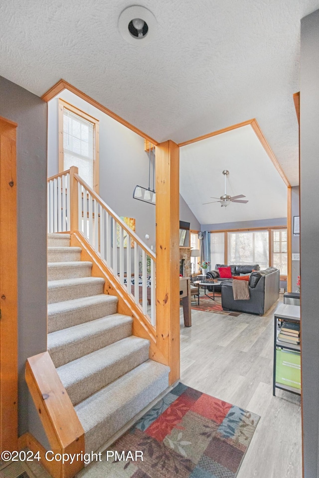 stairway featuring ornamental molding, vaulted ceiling, a textured ceiling, and wood finished floors