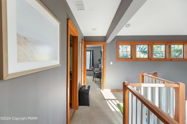 corridor featuring carpet, visible vents, baseboards, and an upstairs landing