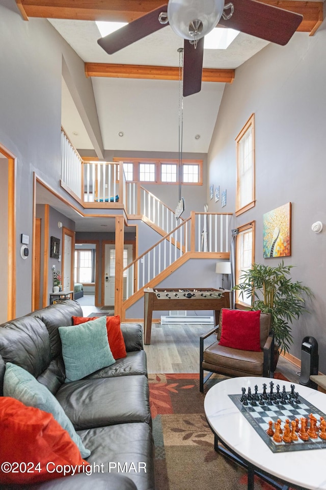 living area featuring stairs, high vaulted ceiling, wood finished floors, and beam ceiling