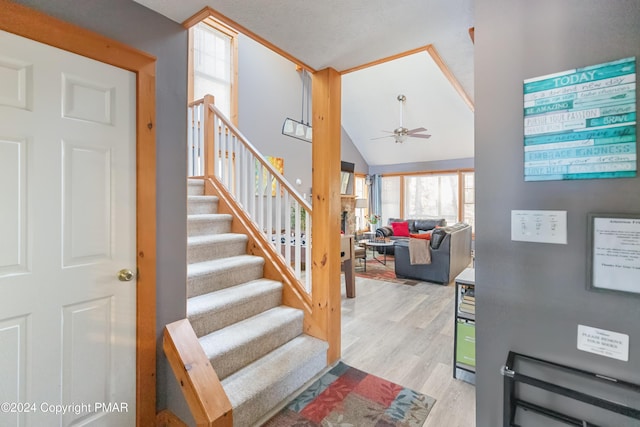 stairway with lofted ceiling, ceiling fan, and wood finished floors