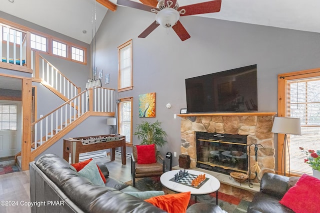 living area featuring high vaulted ceiling, a fireplace, stairway, and wood finished floors