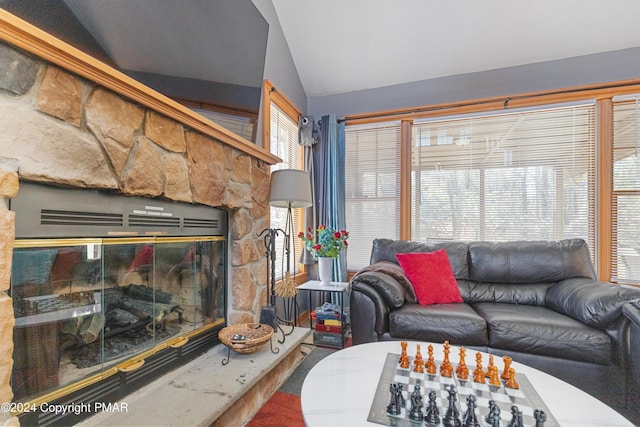 living area with lofted ceiling and a stone fireplace