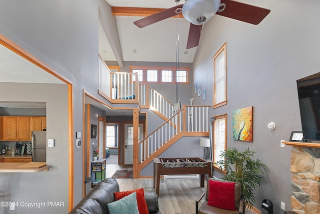 living room with wood finished floors, ceiling fan, a towering ceiling, and stairs