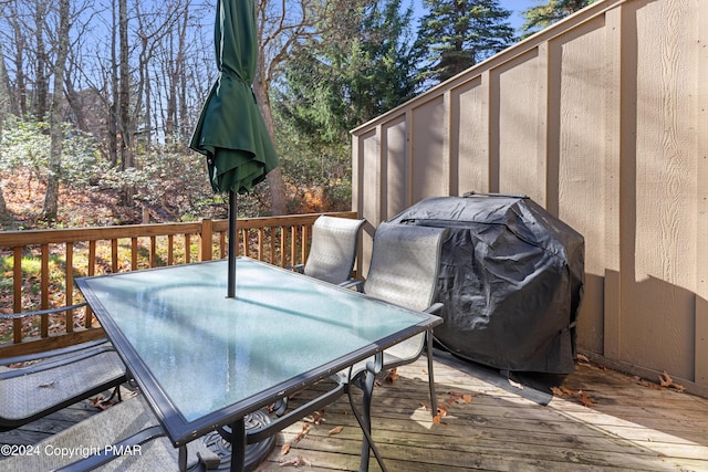 wooden terrace with outdoor dining space and grilling area