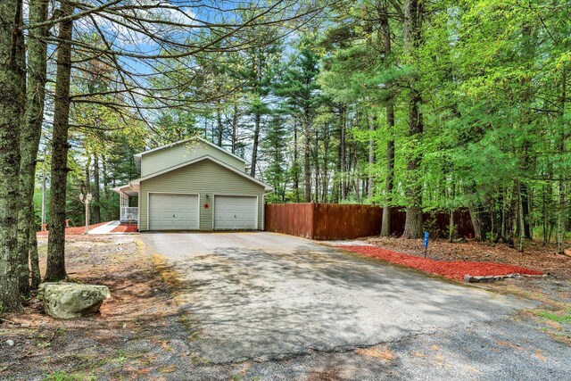 146 Bernadette Dr, Dingmans Ferry, PA 18328 - garage featuring fence, driveway, and a wooded view