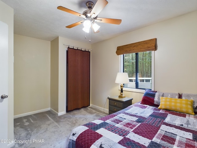 bedroom with baseboards, a ceiling fan, a textured ceiling, carpet floors, and a closet