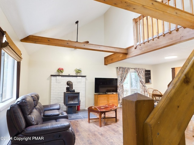 living area with stairs, beamed ceiling, wood finished floors, and a wood stove