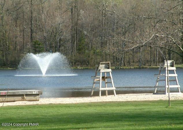 view of dock featuring a yard, a water view, and a wooded view