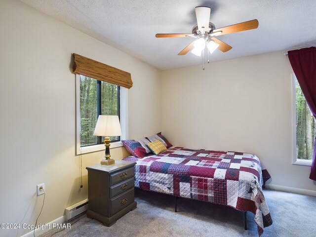 bedroom with ceiling fan, a textured ceiling, a baseboard heating unit, baseboards, and carpet