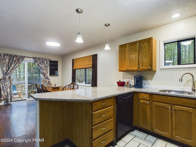 kitchen featuring black dishwasher, brown cabinetry, light stone counters, a peninsula, and a sink