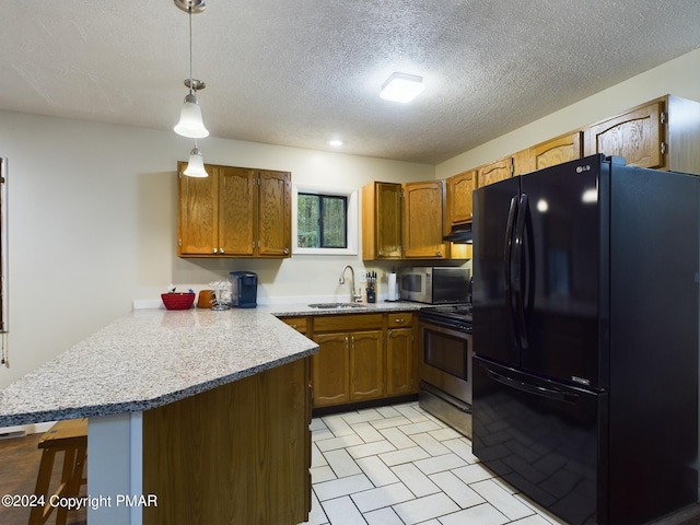 kitchen featuring stainless steel appliances, brown cabinetry, a peninsula, and a sink