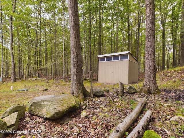 view of yard with an outbuilding, a forest view, and a storage unit