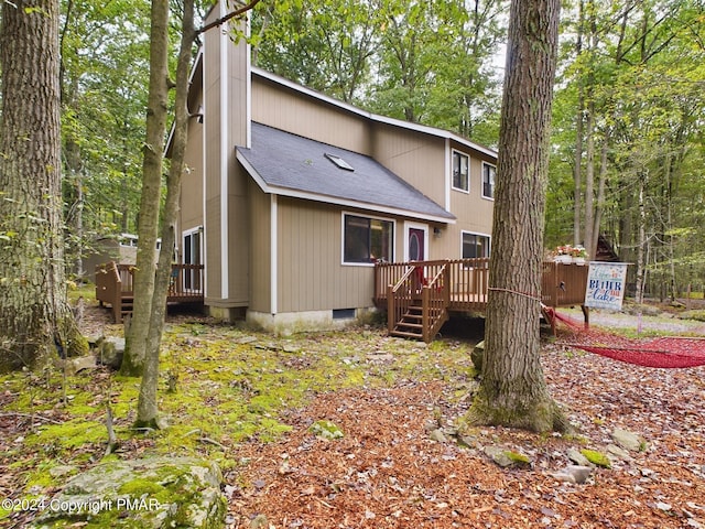 rear view of house featuring a shingled roof and a wooden deck