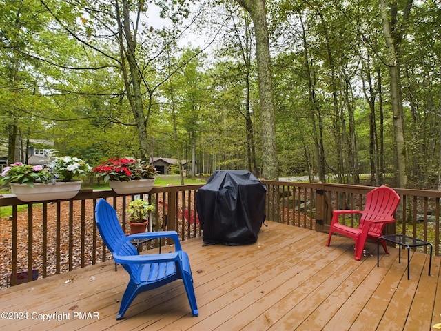 wooden terrace featuring a view of trees and area for grilling