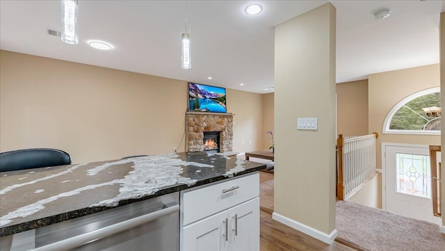 4580 Briarcliff Ter, Tobyhanna, PA 18466 - kitchen with white cabinetry, dark stone counters, a stone fireplace, dishwasher, and light wood-type flooring