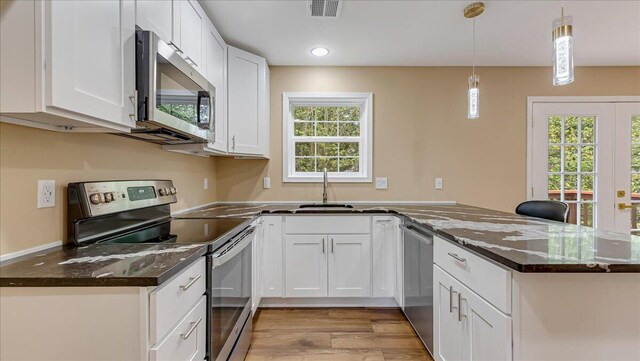 4580 Briarcliff Ter, Tobyhanna, PA 18466 - kitchen with appliances with stainless steel finishes, a peninsula, light wood finished floors, white cabinetry, and decorative light fixtures