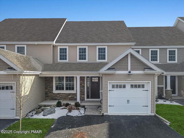 view of front of house featuring stone siding, roof with shingles, driveway, and an attached garage