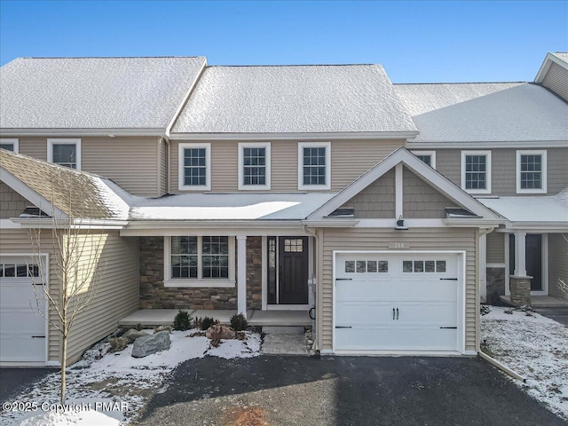 view of front facade with a porch, stone siding, an attached garage, and aphalt driveway