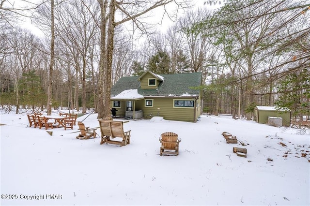 snow covered rear of property featuring a storage unit