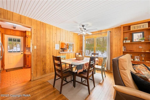 dining space with light wood-type flooring and wooden walls