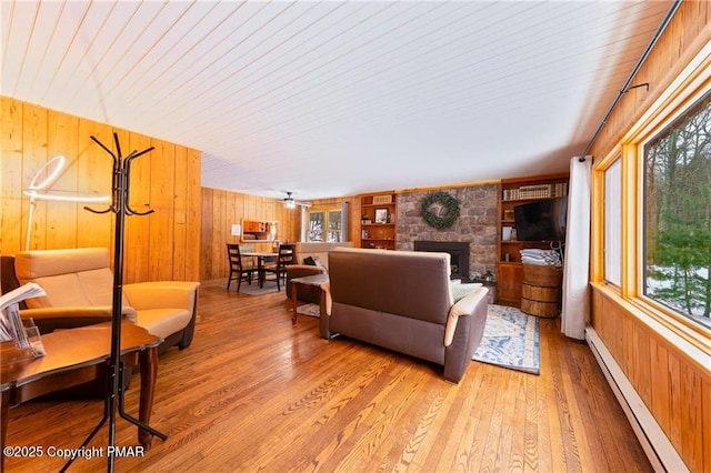 living room featuring a fireplace, light hardwood / wood-style flooring, wooden walls, and baseboard heating