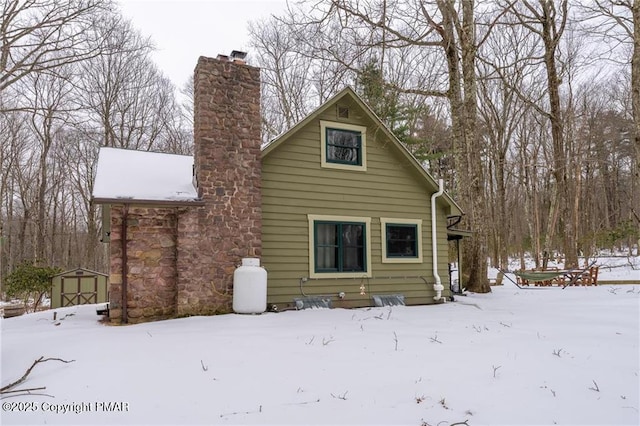 snow covered back of property with a shed