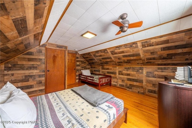 bedroom with light hardwood / wood-style floors, vaulted ceiling, and wooden walls