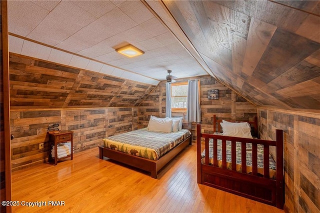 bedroom with vaulted ceiling, hardwood / wood-style floors, and wood walls