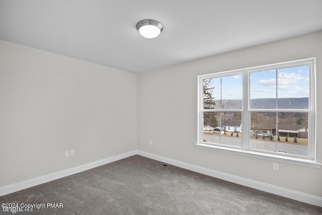 spare room featuring baseboards and dark colored carpet