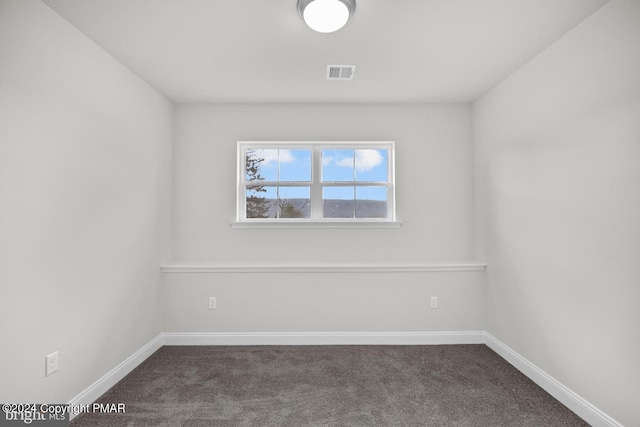 empty room featuring dark carpet, visible vents, and baseboards