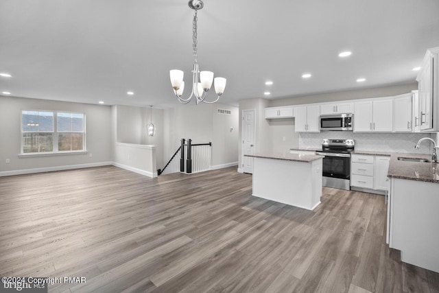 kitchen featuring stainless steel appliances, visible vents, backsplash, light wood-style flooring, and a sink