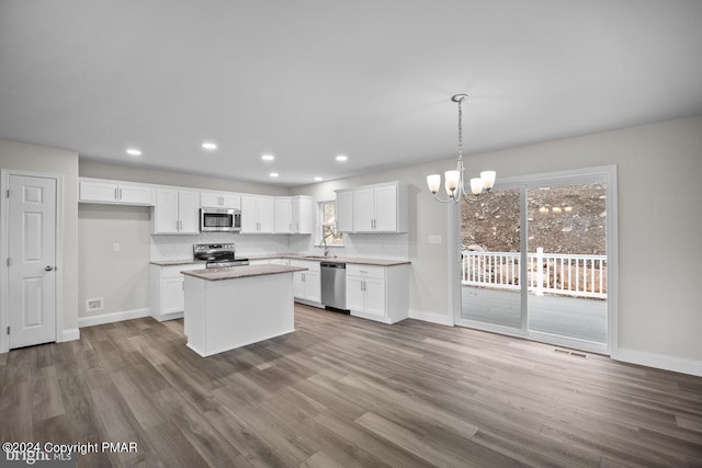 kitchen with appliances with stainless steel finishes, white cabinets, dark wood finished floors, and decorative backsplash