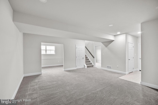 below grade area with baseboards, visible vents, stairway, carpet, and recessed lighting