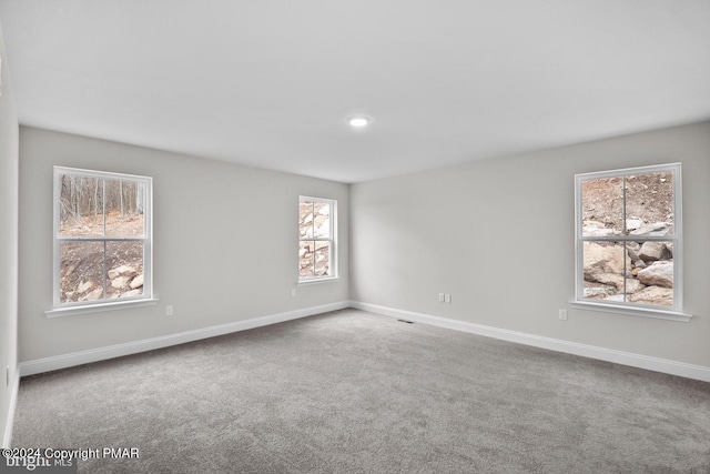 carpeted empty room featuring visible vents and baseboards