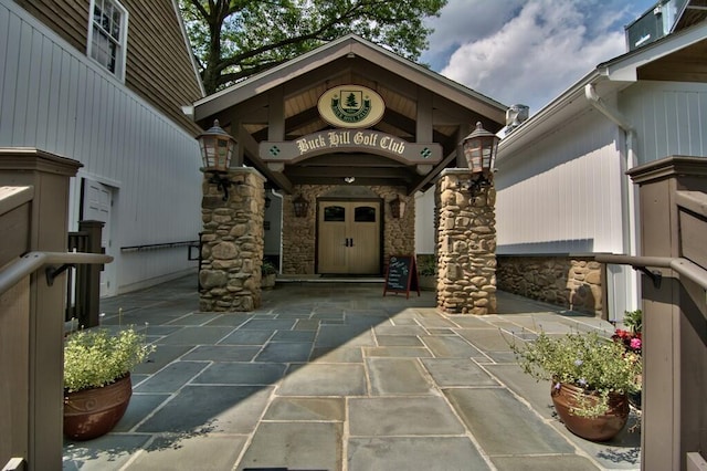 doorway to property with stone siding and a patio