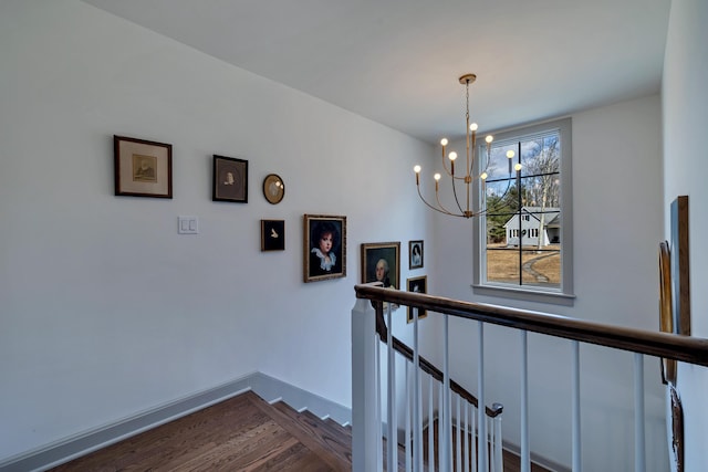 stairway featuring baseboards, an inviting chandelier, and wood finished floors