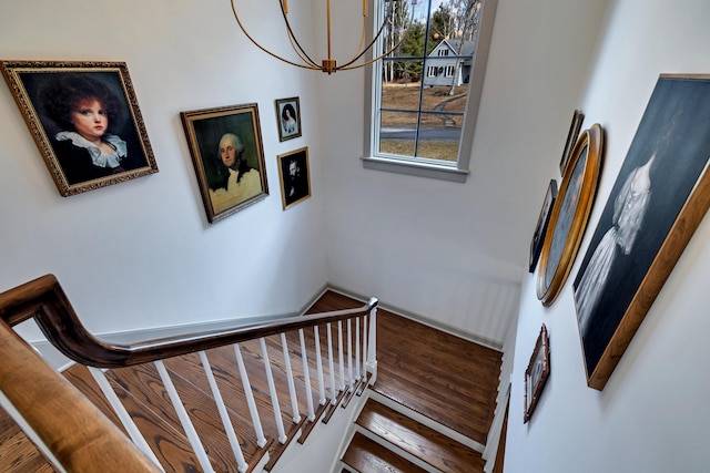 stairway with an inviting chandelier and wood finished floors