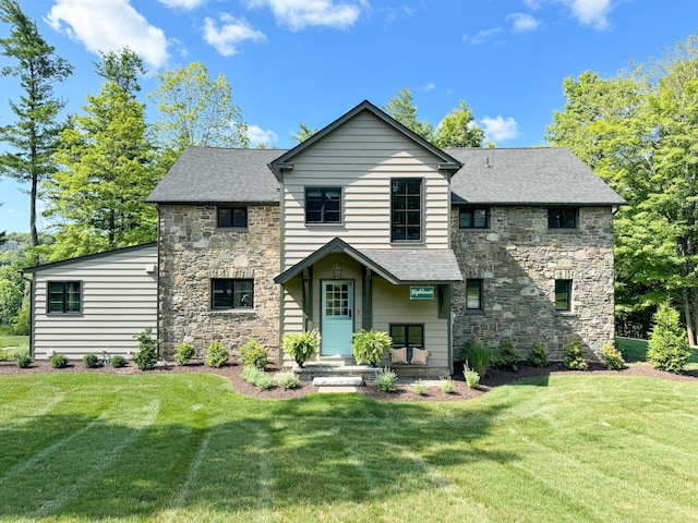 view of front of house featuring a front yard, stone siding, and a shingled roof