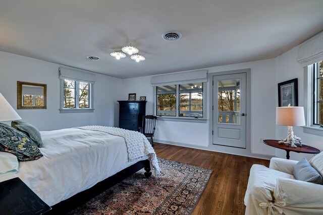 bedroom with wood finished floors, visible vents, and baseboards