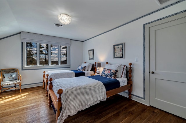 bedroom with visible vents, baseboard heating, and wood finished floors