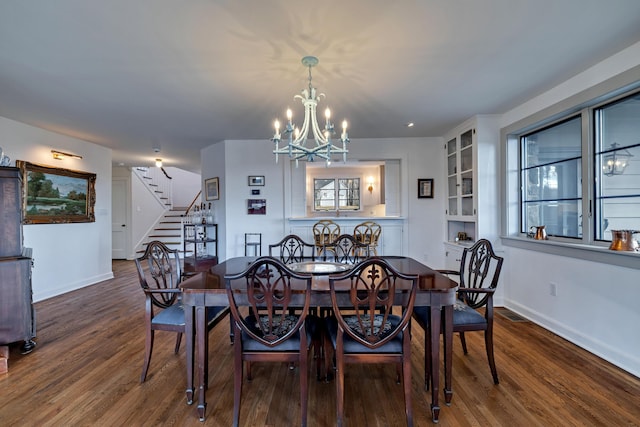 dining space featuring stairs, a notable chandelier, wood finished floors, and baseboards