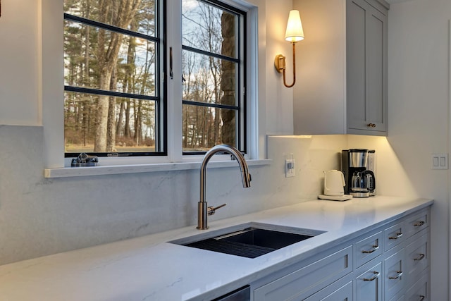 kitchen with a sink, decorative backsplash, and light stone countertops