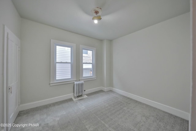 empty room with carpet, radiator heating unit, and baseboards